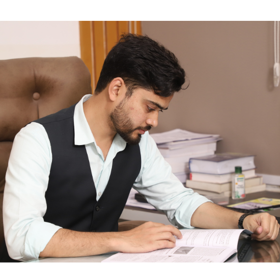 Ashhar Ehtesham, founder of Talent Zone Academy, deeply focused on studying at his office desk, surrounded by books and study materials